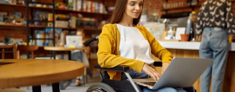 Obrazek wyróżniający w artykule - dofinansowanie do studiów pfron. Studentka na wózku w bibliotece uniwersyteckiej.