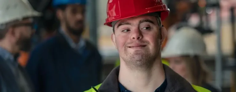 Obrazek wyróżniający do artykułu - lekki stopień niepełnosprawności - przedstawia pracownika z lekką niepełnosprawnością w stroju służbowym i kasku na głowie.